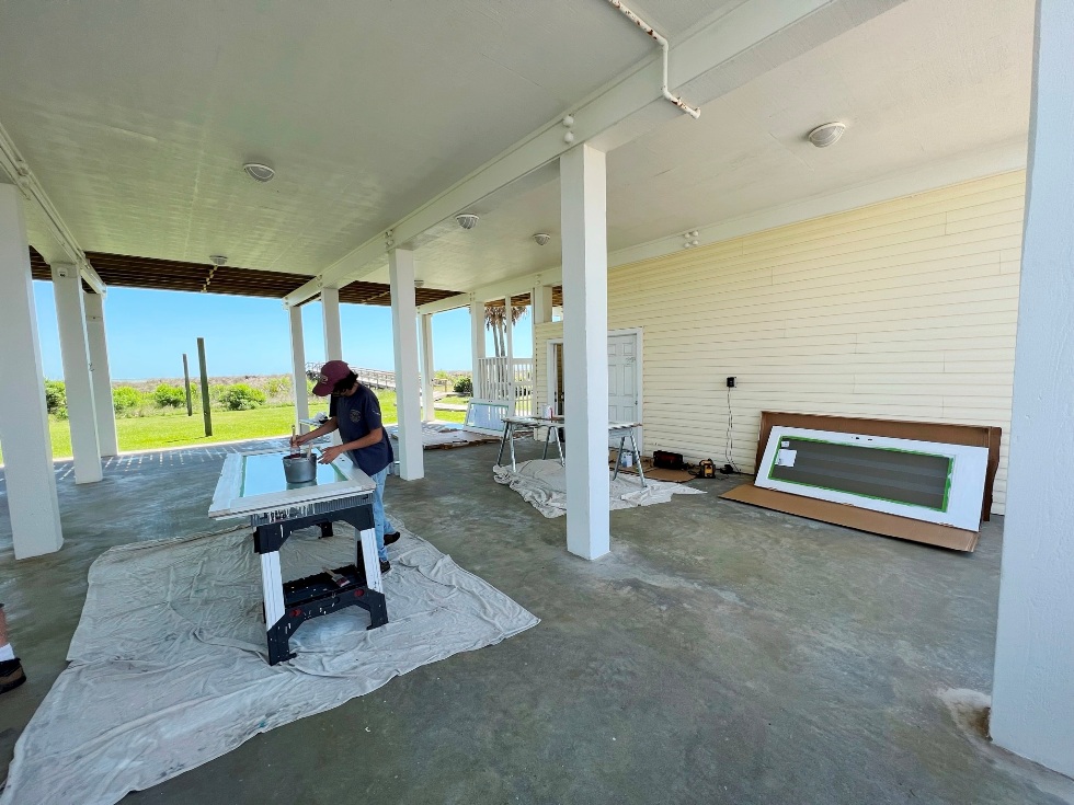 Image of Adam Calvert painting a door as part of a beach house maintenance program in Galveston, Texas.  Image Copyright © 2023 Brad Larkin