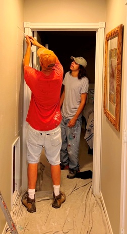 Image of Tracy Calvert Jr and Adam Calvert cutting out bad drywall in a Galveston beach house. Image Copyright © 2022 Brad Larkin