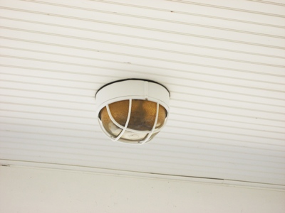 Image of an overhead nautical bulkhead light fixture full of dirt and water following a tropical storm in Galveston, Texas.  Image Copyright © 2008 Brad Larkin