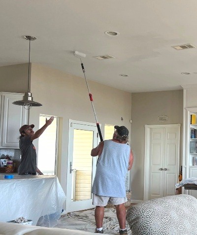Image of Tracy Calvert's crew painting the ceiling of a beach house after fixing a water damage problem.  Image Copyright © 2022 Brad Larkin