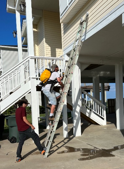 Image of Calvert crew mounting a long ladder for work on a Galveston beach house. Image Copyright © 2022 Brad Larkin
