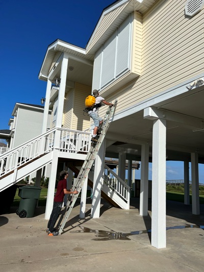 Image of Calvert crew spray cleaning storm shutters on a Galveston beach house. Image Copyright © 2022 Brad Larkin