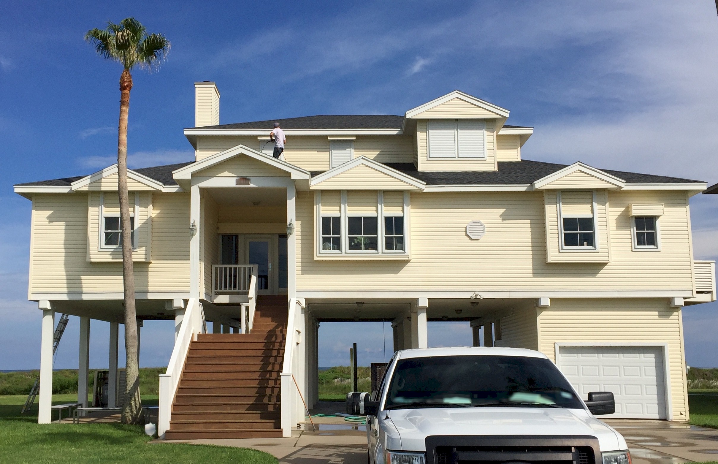 Image of home maintenance technician power washing the upper exterior of a Galveston beach house. Image Copyright © 2019 Brad Larkin