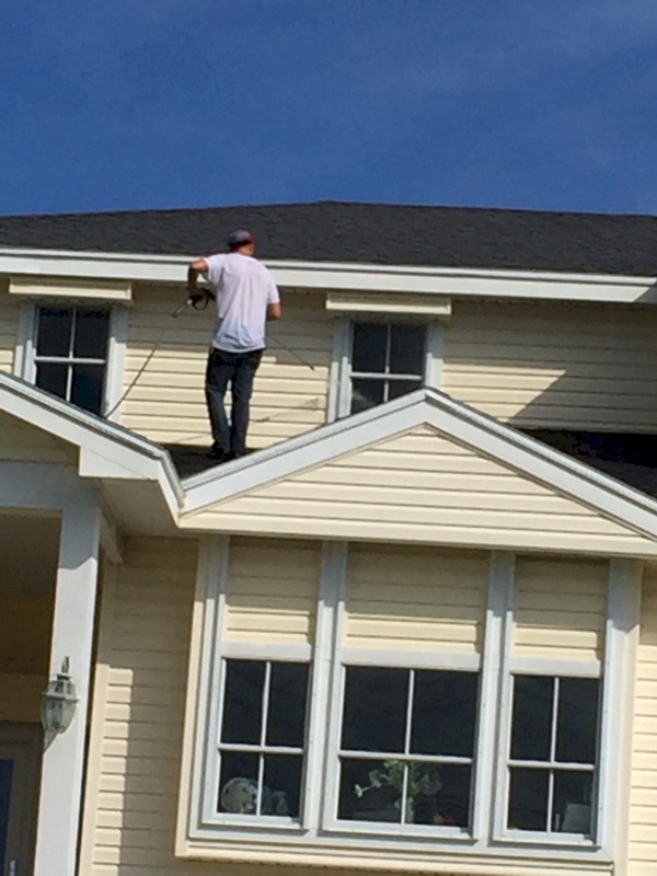 Image of home maintenance technician power washing the upper exterior of a Galveston beach house. Image Copyright © 2019 Brad Larkin