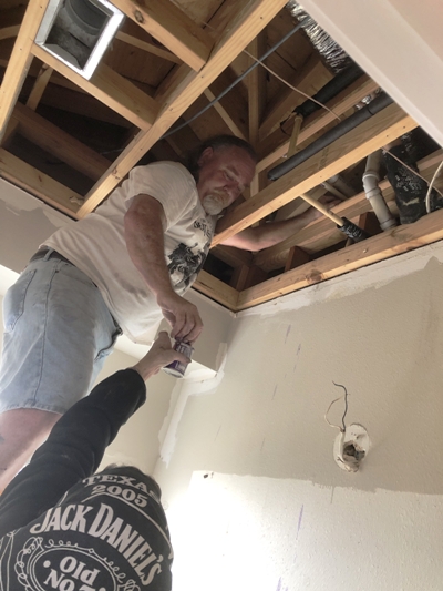 Image of Tracy Calvert Sr working to identify burst pipes in the ceiling of a Galveston house during the 2021 Texas Freeze. Image Copyright © 2021 Brad Larkin
